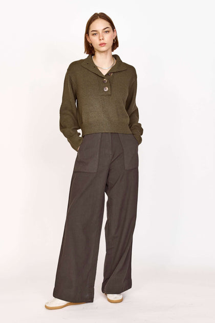 Model wearing an olive green top with buttons paired with wide-leg gray pants for a stylish and casual look.